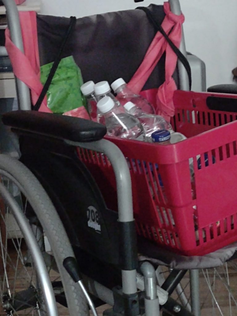 Wózek inwalidzki z koszem zakupowym robiący za śmietnikowóz